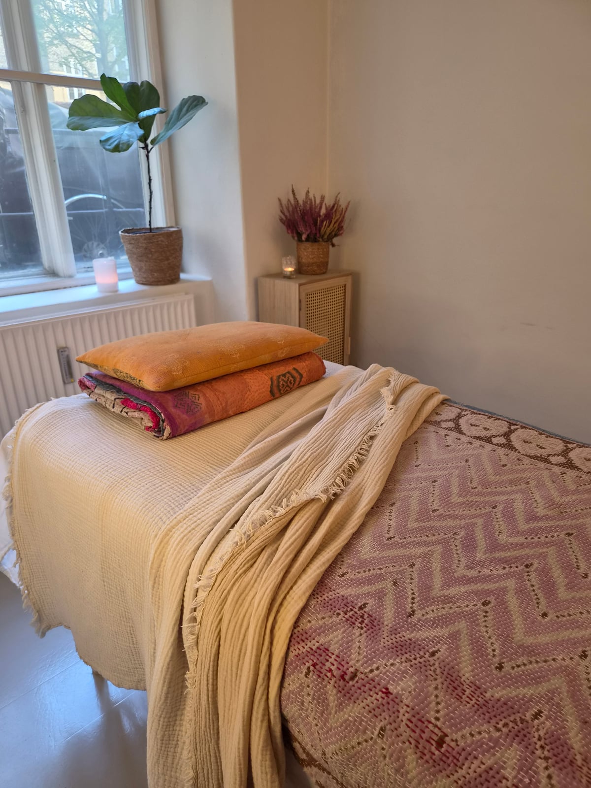 Behandlingsbriks med tæpper og puder i Leas rolige behandlingsrum.